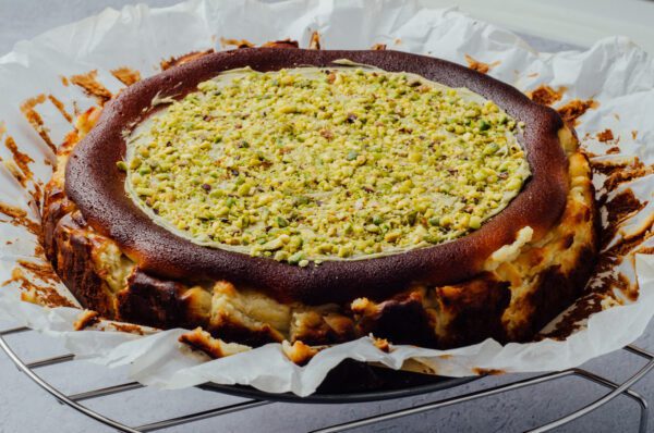 Pistachio baked cheesecake with chopped pistachio topped and pistachio spread at the top of cheesecake